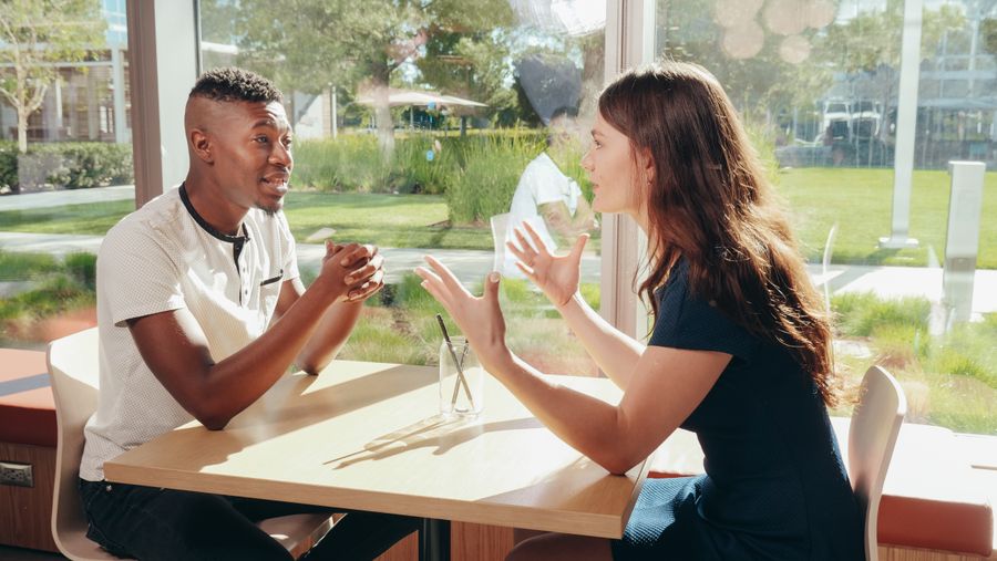 Illustrative photograph of two people having a conversation at a table