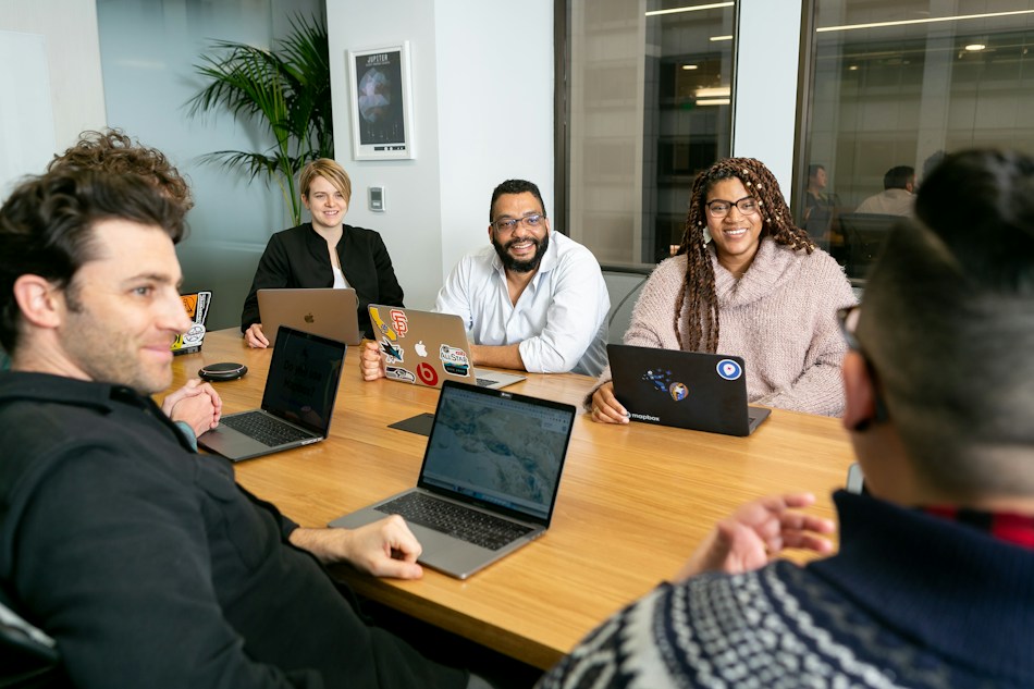 Illustrative team collaborating with laptops in a meeting room